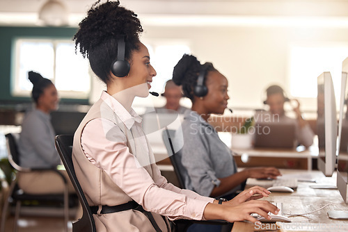 Image of Call center, black woman and computer on desk in office for customer service, sales or support. Agent or consultant team in telemarketing, telecom and crm or help desk in coworking workplace