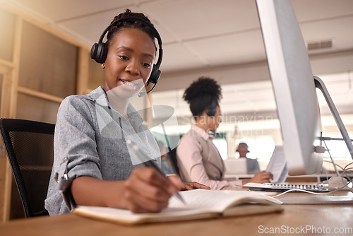 Image of Call center, woman and writing at computer on desk in office for sales and customer service notes and information, African female agent or consultant in telemarketing, support and crm with notebook