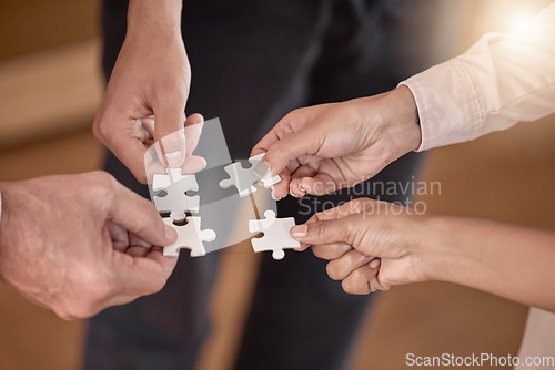 Image of Business people, hands and puzzle piece in planning, collaboration or teamwork brainstorming at the office. Hand of group in team building, strategy or activity for engagement, support or interaction