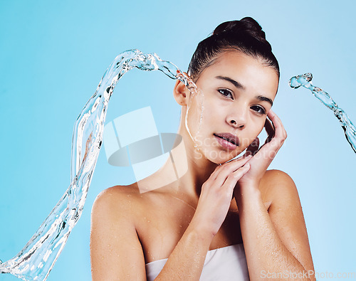 Image of Portrait, cleaning and woman with water, cosmetics and hygiene on a blue studio background. Face, female and person with clear liquid, morning routine and self care with skincare, beauty and wellness