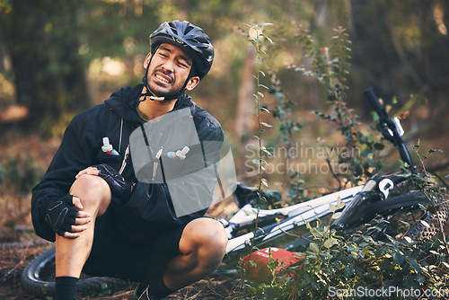 Image of Forest, cycling and Asian man with knee pain, training and muscle tension in nature, emergency and accident. Male rider, athlete or person with bicycle, leg injury and outdoor for practice and strain