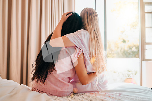 Image of Love, bedroom and back of friends hugging for comfort, support or care while at a sleepover. Bond, romance and lesbian women couple embracing and spending quality time together in their apartment.