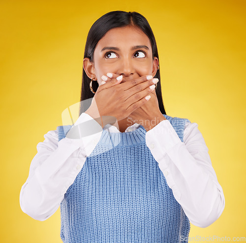 Image of Shock, omg and young female in a studio with her hand on her mouth for a wtf expression. Shocked, ecstatic and Indian woman model with wow or surprise face for good news isolated by yellow background