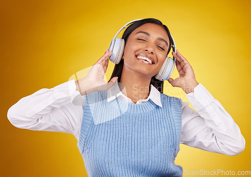 Image of Music headphones, studio and happy woman listening to media sound track for fun, freedom and wellness. Energy, audio podcast or Indian person streaming radio, playlist or song on yellow background