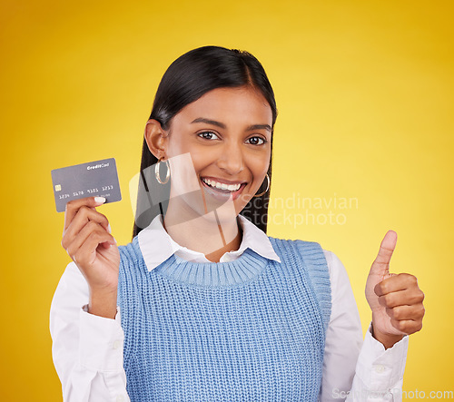 Image of Credit card, thumbs up and portrait of Indian woman on yellow studio for bank, investment and payment. Banking mockup, finance and happy girl with yes hand sign for budget, commerce and purchase