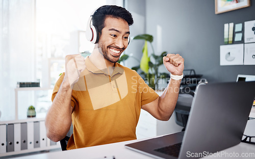 Image of Business man, laptop and headphones to celebrate success while listening to music, audio or video call. Asian male entrepreneur at desk with a smile and hands for achievement, notification or goals