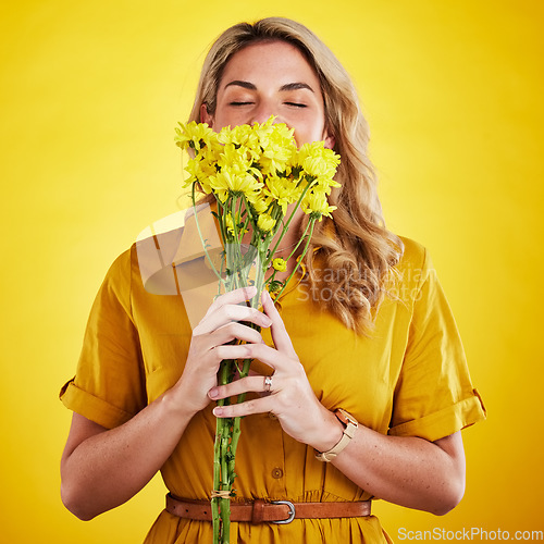 Image of Portrait, smelling and woman with flowers in studio isolated on a yellow background. Floral, bouquet and person sniff, aroma or scent with female model holding natural plants and fresh flower.