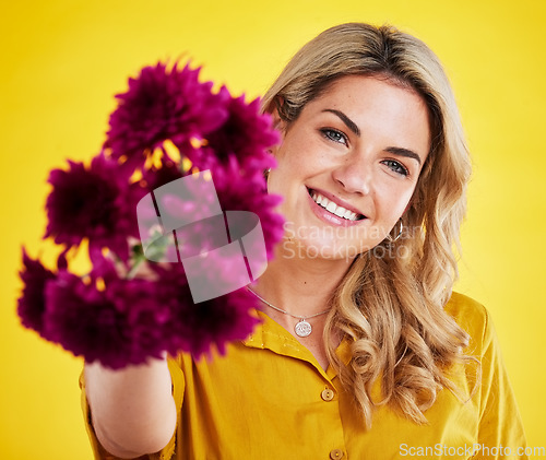 Image of Portrait, happiness and woman giving flowers in studio isolated on a yellow background. Floral, bouquet present and smile of female person holding gift of natural plants, purple flower or dahlia.