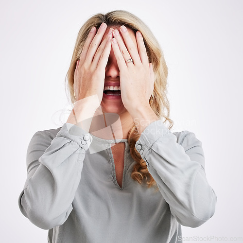 Image of Comic, funny and embarrassed with a woman on a gray background in studio laughing at a joke. Smile, comedy and humor with a person enjoying a laugh or fun while covering her face in expression