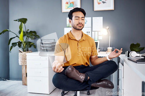 Image of Yoga, night and business man in office for mental health, relax and breathing exercise at a desk. Corporate, meditation and asian guy manager meditating for stress management, zen and peace in Japan