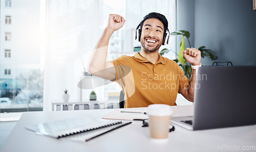 Image of Laptop, headphones and business man celebrate success while listening to music, audio or video call. Excited asian male entrepreneur at desk with smile and hands for achievement, win or goals