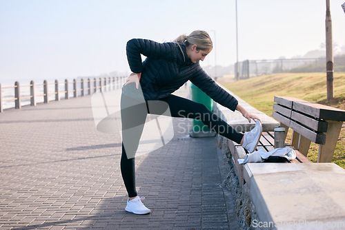 Image of Runner, woman and stretching legs at the beach for training, running and morning cardio routine outdoors. Run, warm up and girl stretch before fitness, exercise and sports workout along the ocean