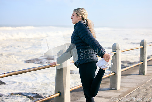 Image of Woman, runner and stretching legs at the beach for training, running and morning cardio routine outdoors. Run, warm up and stretch before fitness, exercise and sports workout along the ocean