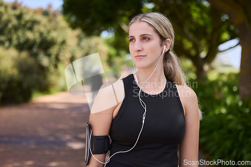 Image of Headphones, runner or woman thinking in park training, exercise or workout for a healthy body. Wellness, fitness break or sports girl athlete exercising or streaming audio or radio song in nature