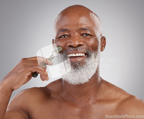 Image of Face roller, portrait or senior man with skincare, stone or dermatology product for skin glow. Elderly, cheek and facial roll of a African male model doing self care for grooming with jade for beauty