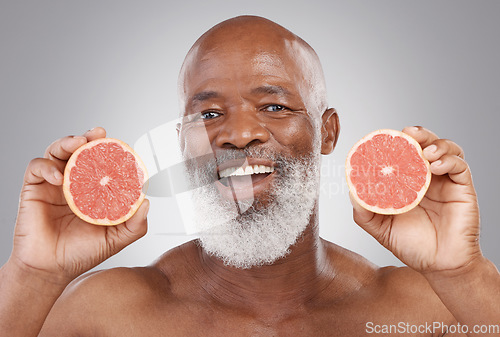 Image of Senior black man, grapefruit and smile for vitamin c, healthy skincare or natural nutrition against gray studio background. Portrait of happy African male with fruit for skin, healthcare or wellness