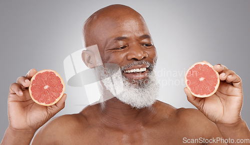 Image of Senior black man, grapefruit and smile for skincare, natural nutrition or vitamin c against a gray studio background. Happy African American male holding fruit for healthy skin, diet or wellness