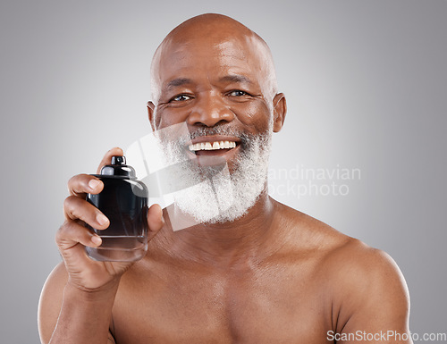 Image of Perfume, smile and portrait of senior black man model feeling happy and excited isolated in a gray studio background. Self care, skincare and old male person holding cologne for fragrance in backdrop