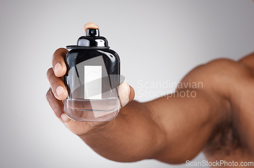 Image of Hand, bottle and cologne with a man in studio on a gray background holding a perfume fragrance product. Luxury scent, glass and spray with a male showing a container of cosmetics for a fresh smell