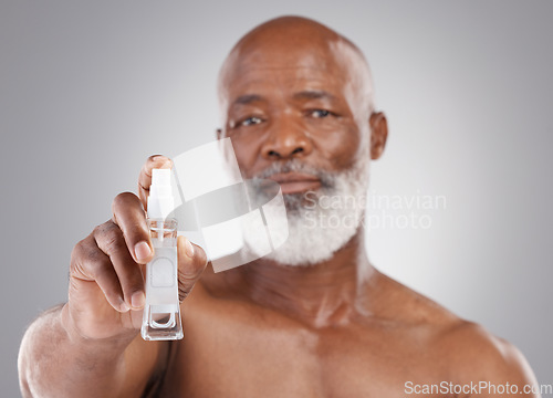 Image of Portrait, skincare and serum with a senior man holding an antiaging product in studio on a gray background. Face, beauty and cosmetics with a mature male spraying a facial treatment for beard care