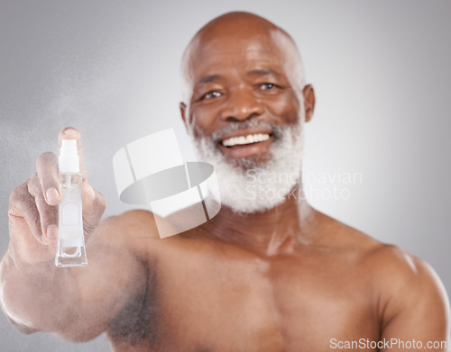 Image of Portrait, beauty and product with a senior man holding an antiaging serum in studio on a gray background. Face, beard care and cosmetics with a mature male spraying a facial treatment for skincare