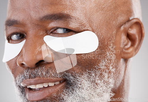 Image of Skincare, collagen and eye mask for a portrait of black man with smile, happiness or anti ageing face treatment. Closeup dermatology, grooming or happy mature model with patches on eyes for skin care