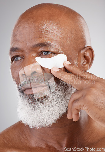 Image of Skin care, collagen eye mask and black man with hand on face on studio background for professional anti ageing spa treatment. Dermatology, cosmetic process and mature model with skincare on eyes.