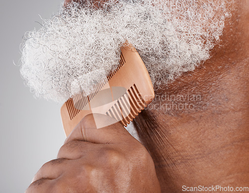 Image of Man, hands and beard with comb in grooming, beauty or skincare hygiene against a studio background. Closeup of senior male neck and chin combing or brushing facial hair for clean wellness or haircare