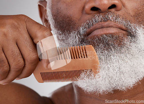 Image of Senior black man, hands and beard with comb in grooming, beauty or skincare hygiene against a studio background. Closeup of African elderly male face combing or brushing facial hair in clean wellness