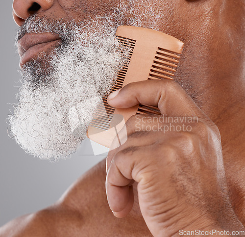 Image of Man, hands and closeup of beard with comb in grooming, beauty or skincare hygiene against a studio background. Senior male neck and chin combing or brushing facial hair for clean wellness or haircare