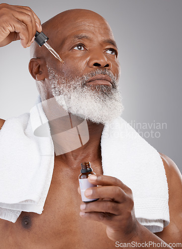 Image of Skincare, health and male with face serum in a studio for a natural, beauty and skin treatment. Cosmetic, wellness and senior man model with facial oil for a dermatology routine by a gray background.