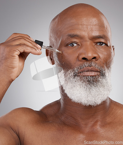 Image of Skincare, portrait and man with face serum in a studio for a natural, beauty and skin treatment. Cosmetic, health and senior male model with facial oil for a wellness routine by a gray background.