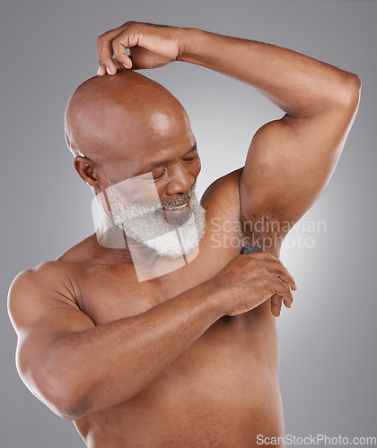 Image of Senior black man, deodorant and armpit for skincare, grooming or person hygiene against a gray studio background. Happy elderly African American male applying cosmetics for fresh or clean smell