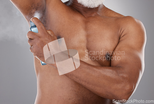Image of Senior black man, deodorant and spraying armpit for skincare, grooming or personal hygiene against a gray studio background. Elderly African American male applying cosmetics for fresh or clean smell