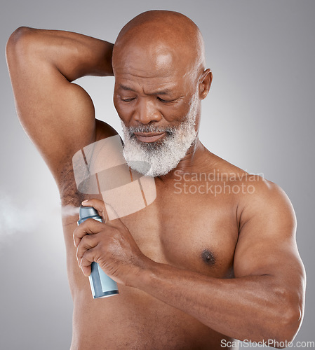 Image of Senior black man, deodorant and armpit for hygiene, grooming or perfume against a gray studio background. Serious elderly African American male spraying cosmetics for fresh fragrance or clean smell