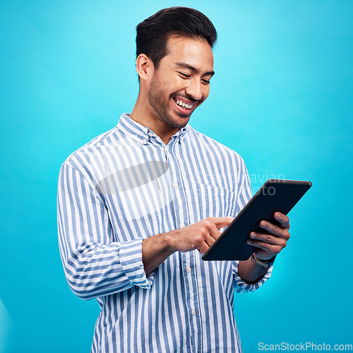 Image of Tablet, man and smile in a studio on social media, internet and website app scroll. Happiness, isolated, and blue background with a male model reading a ebook on a digital networking application