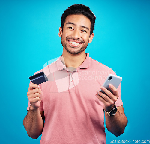 Image of Man with smartphone, credit card and smile in portrait, ecommerce and fintech isolated on blue background. Online shopping, internet banking and finance, technology and male with bank app in studio