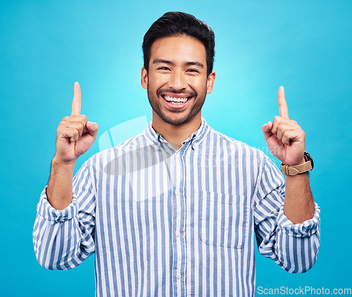 Image of Point, happy and portrait of Asian man on blue background for news, information and announcement. Advertising, studio mockup and face of excited male pointing for copy space, promo and showing sign