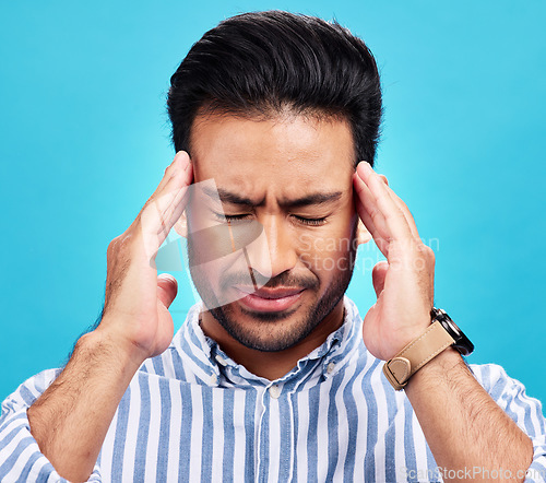 Image of Man with headache, pain and stress with anxiety and mental health problem or crisis isolated on blue background. Male person hands holding head, massage temple with depression and migraine in studio