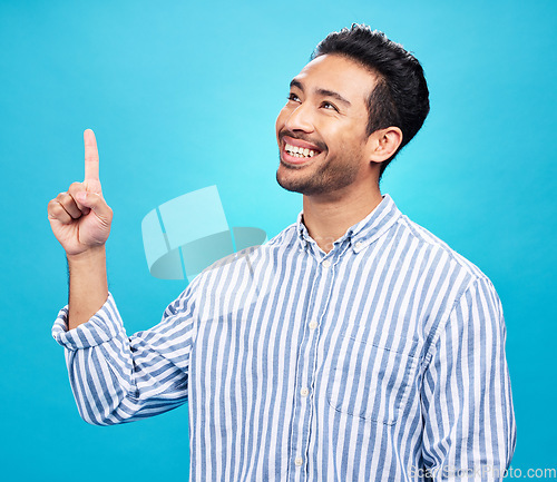 Image of Point, thinking and man on blue background for news, information and announcement in studio. Advertising, mockup sign and face of excited male pointing for copy space, promotion and showing gesture