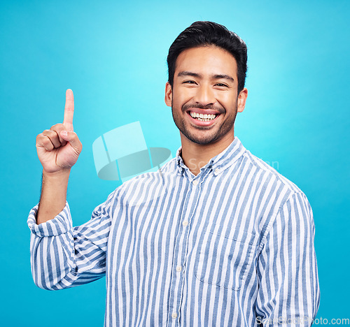Image of Point, excited and portrait of Asian man on blue background for news, information and announcement. Advertising, studio mockup and happy male pointing for copy space, promotion and showing gesture