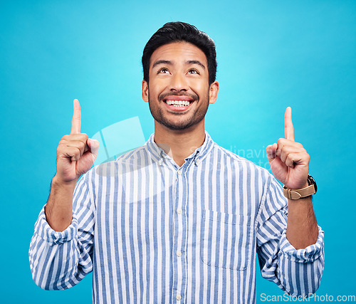 Image of Man is pointing up, marketing and promotion with happiness and branding isolated on blue background. Opportunity, deal or announcement with advertising, news and promo ad with male person and smile