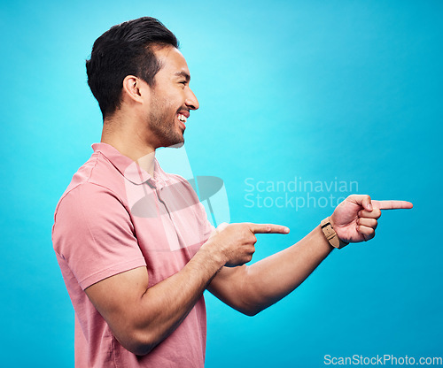 Image of Mockup, happy and man point on blue background for news, information and deal announcement. Advertising, branding and excited male pointing for copy space, promotion and showing gesture in studio