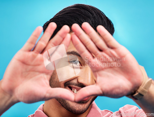 Image of Frame, hands and portrait of Asian man on blue background with smile, confidence and happiness. Perspective, framing and face of happy male in studio for photography, profile picture and vision sign