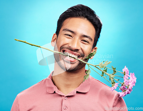 Image of Teeth, flower and happy with portrait of man in studio for celebration, gift and romance. Funny, goofy and present with male isolated on blue background for happiness, smile and valentines day mockup