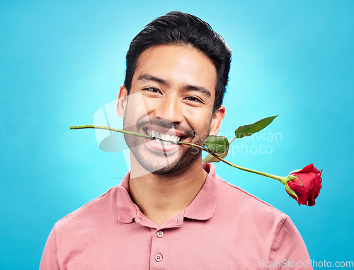 Image of Teeth, flower and rose with portrait of man in studio for celebration, gift and romance. Funny, goofy and present with male isolated on blue background for happiness, smile and valentines day mockup