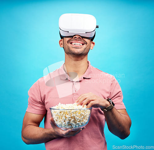 Image of Vr, popcorn and movie with man in studio for streaming, met verse and cinema. Happy, technology and digital with male watching tv on blue background for virtual reality, television and future theater