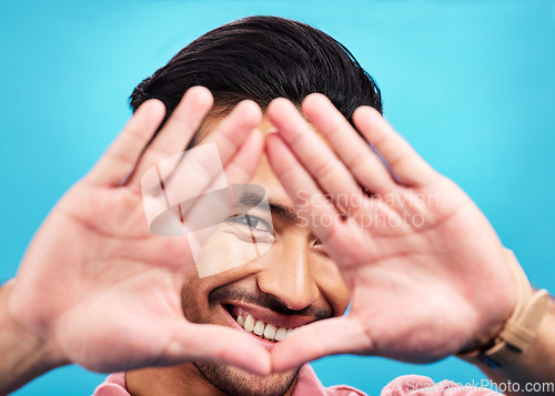 Image of Frame, hands and portrait of happy Asian man on blue background with smile, confidence and happiness. Perspective, shape and face of male person in studio for photography, profile picture and vision