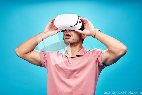 Image of Man, virtual reality and surprise with UX and metaverse, futuristic technology isolated on blue background. Gamer, VR headset or goggles, male person in digital world with wow expression in studio