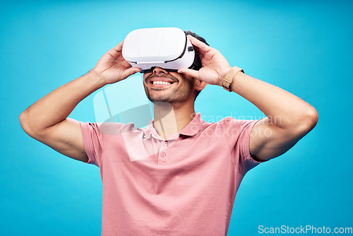 Image of Man with smile, virtual reality and metaverse with futuristic tech, UX and simulation isolated on blue background. Future technology, digital world and gaming male in VR goggles streaming in studio